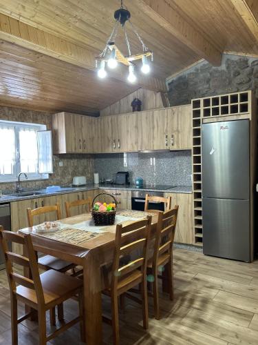 a kitchen with a table with chairs and a refrigerator at Cantinho da Aldeia in Castedo