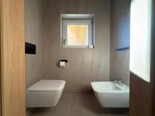 un bagno con un water, un lavandino e una finestra di Liz Hotel & Apartments a Predazzo