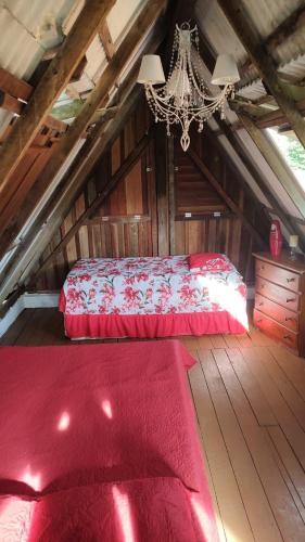 a bedroom with a red bed in a attic at Chalé Maison Blanche in Maracanã