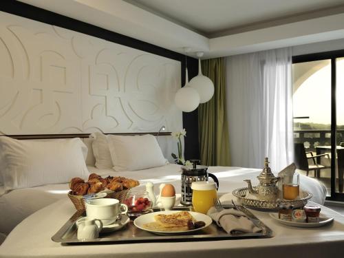 a breakfast tray on a bed in a hotel room at Pullman Mazagan Royal Golf & Spa in El Jadida