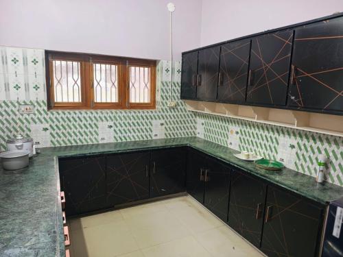 an empty kitchen with black cabinets and green tiles at Elixir Mansion in Jāmb