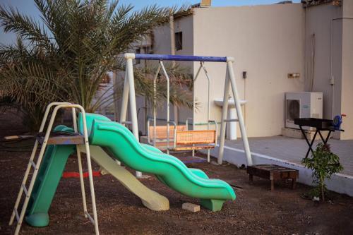 a playground with a slide in a yard at Farm house with all facilities in Al Dhaid , sharjah in á¸¨aÅŸat al BidÄ«yah