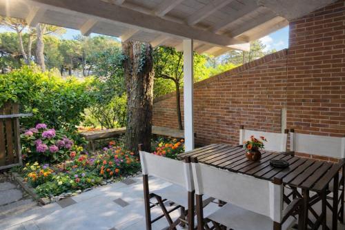 een houten tafel en stoelen op een patio met bloemen bij Paradise house & garden in Lignano Sabbiadoro