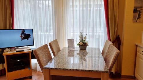 a dining room with a table with chairs and a television at Dünenschloss - 02-14 inkl Strandkorb in Kühlungsborn