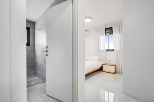 een witte slaapkamer met een bed en een douche bij Spacious Family Luxury Getaway in Ashdod