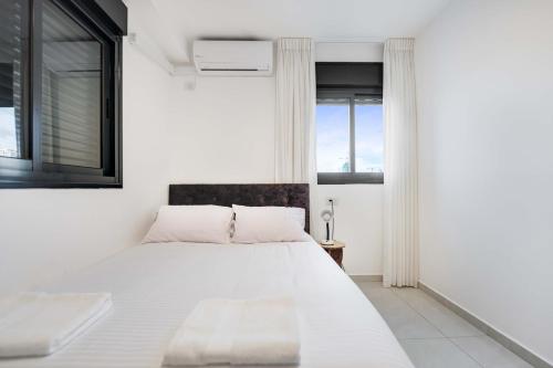 een witte slaapkamer met een groot bed en ramen bij Spacious Family Luxury Getaway in Ashdod