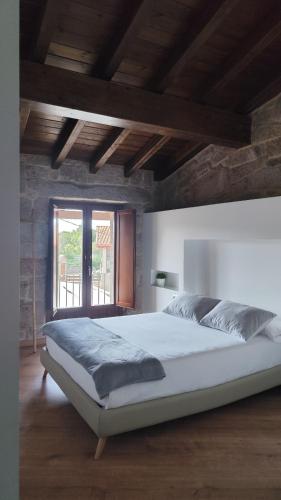 a bedroom with a large white bed with a window at Casa Vilar de Flores in Ourense