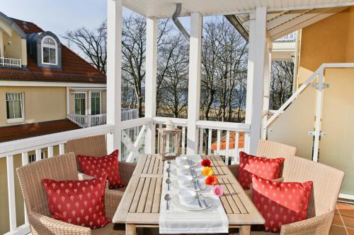 een tafel op een veranda met rode kussens bij Dünenschloss - 02-24 in Kühlungsborn