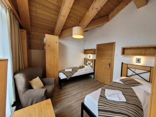 a bedroom with two beds and a chair in a room at Chalets Jasná Centrum APARTMENT M - Free Jacuzzi & Sauna and Chopok view in Belá
