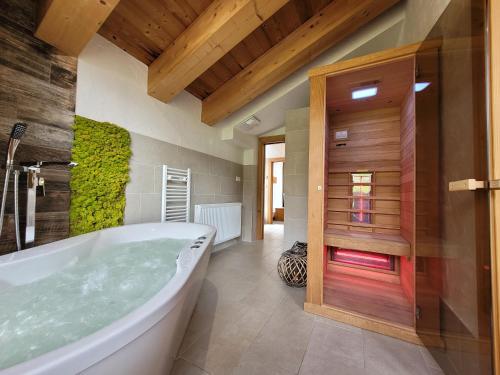 a bathroom with a large tub and a wooden door at Chalets Jasná Centrum APARTMENT M - Free Jacuzzi & Sauna and Chopok view in Belá