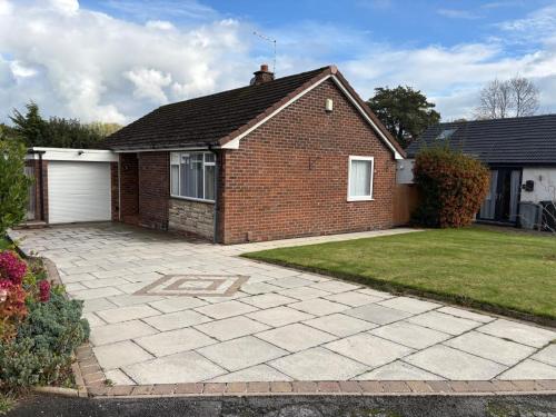 a brick house with a garage and a yard at The Knutsford Bungalow in Knutsford