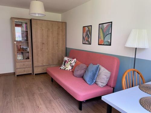a living room with a pink couch with pillows on it at Wygodne mieszkanie dla dwojga in Bystrzyca Kłodzka