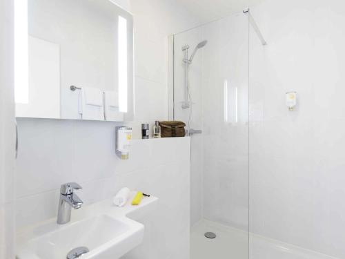 a white bathroom with a shower and a sink at Résidence Studio Genève Centre in Geneva