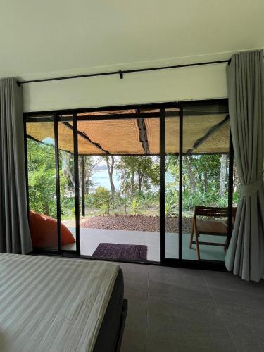 a bedroom with a bed and a large window at Spiral Resort in Ko Phayam