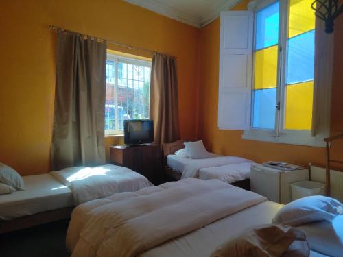 een kamer met 3 bedden, een tv en ramen bij De Gino Hostal in El Cerrillo