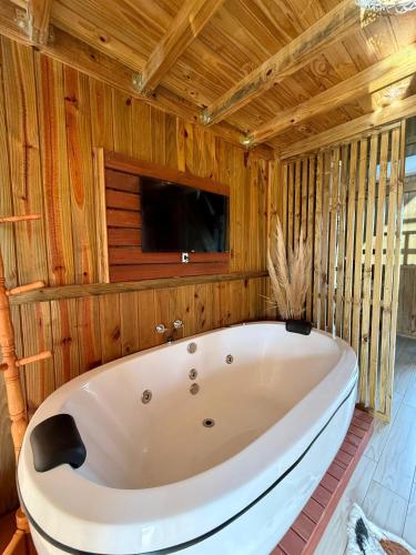 a large white tub in a room with wooden walls at Chalé Rústico com Hidromassagem e Piscina in Imaruí