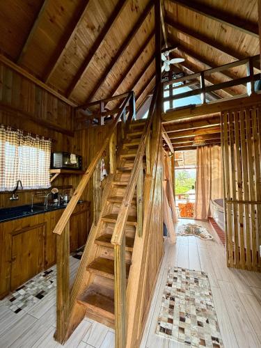a wooden staircase in a room with a kitchen at Chalé Rústico com Hidromassagem e Piscina in Imaruí