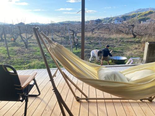 a hammock on a deck with a man and a horse at 柿畑の宿 Private stay with farm and house all to yourself in Katsuragi