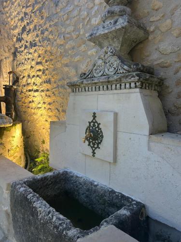 a stone fountain with a clock on the side of a building at Maison des Passeroses in Boutiers-Saint-Trojan