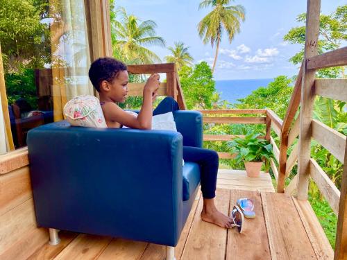 a boy sitting in a blue chair reading a book at 7 Ventos in Alto Douro