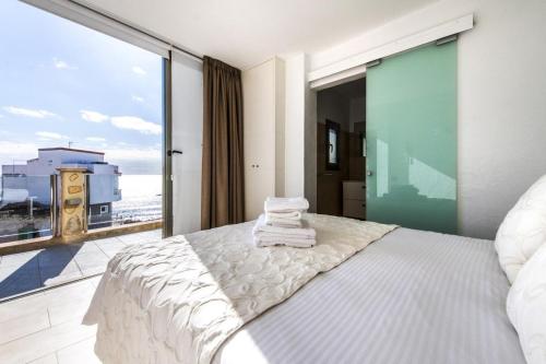 een wit bed in een kamer met een groot raam bij Apartment Aguamarina El Cotillo Adults Only in Cotillo
