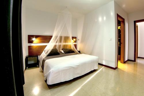 een slaapkamer met een wit bed en een klamboe bij Casa Maeva with heated pool in El Roque in Cotillo