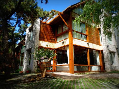 una casa con puertas de cristal y un árbol en Hostería y Cabañas Altamar De Las Pampas en Mar de las Pampas