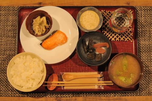 a tray of food with a plate of food and chopsticks at Hostel&Bar CAMOSIBA in Yokote