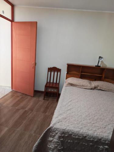 a bedroom with a bed and a chair and a door at Habitaciones en la Casa de Dora, 4to y 5to piso in Ayacucho
