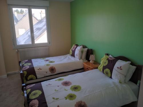 two beds in a room with a window at La Petite Maison Celtique in Saint-Nicolas-du-Pélem