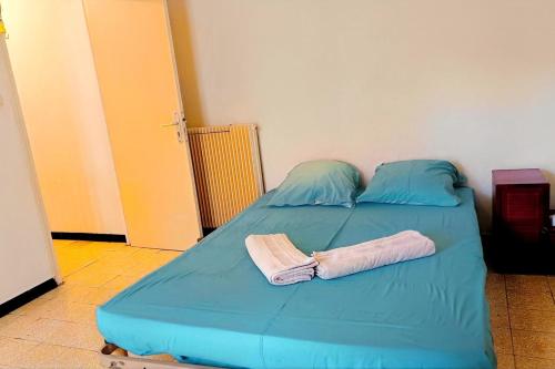 a blue bed with two pillows and two towels on it at Spacious house in Perpignan quiet and friendly in Perpignan