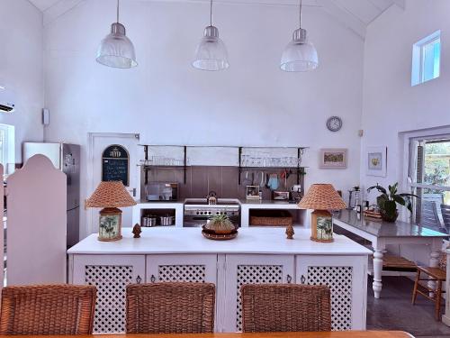 een keuken met een wit kookeiland met twee lampen bij Skuurtjie in Prince Albert
