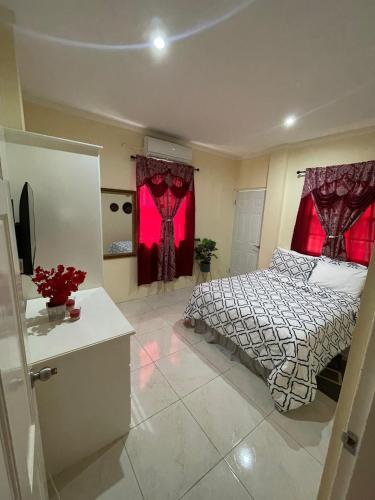 a bedroom with a bed and two windows with red curtains at Rivière Chateau - Gros Islet in Gros Islet