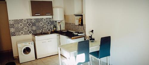eine Küche mit einer Waschmaschine, einem Tisch und Stühlen in der Unterkunft apartement des Romains in Sospel