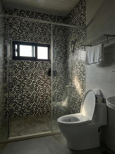 a bathroom with a toilet and a glass shower at OFFLand 遺忘無際 宜蘭 4-6人 小包棟民宿 in Wujie