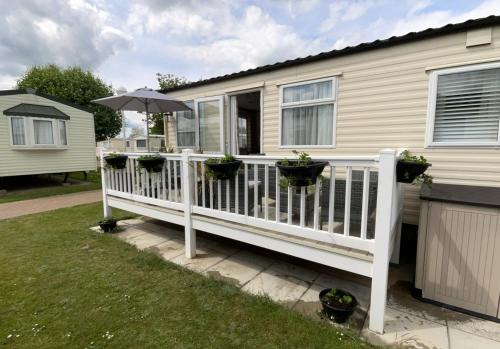 a white deck with an umbrella and potted plants at Seaside Sanctuary in Hemsby