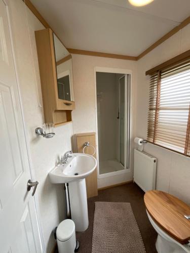 a small bathroom with a sink and a toilet at Seaside Sanctuary in Hemsby