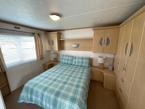 a small room with a bed with a plaid blanket at Seaside Sanctuary in Hemsby