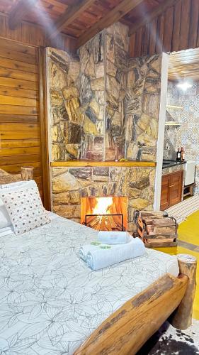a bed in a room with a stone wall at Pousada Portal do Céu in Visconde De Maua