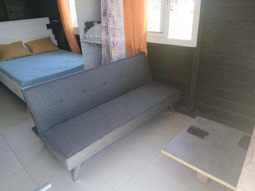 een bank in een kamer met een bed en een raam bij Bungalow citron in Petit-Bourg