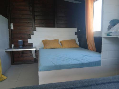 a bed with two pillows on it in a room at Bungalow citron in Petit-Bourg