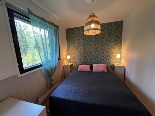 een slaapkamer met een bed met twee roze kussens en een raam bij Huvikumpu in Orivesi