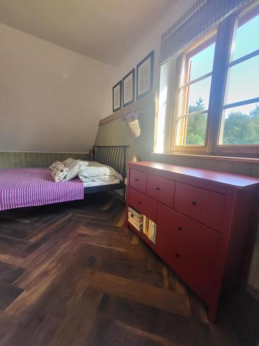 a bedroom with a bed and a dresser and windows at Chata Kolmanovci in Oščadnica