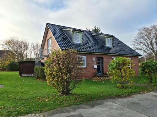 a red brick house with a black roof at Küstenhuus in Utersum