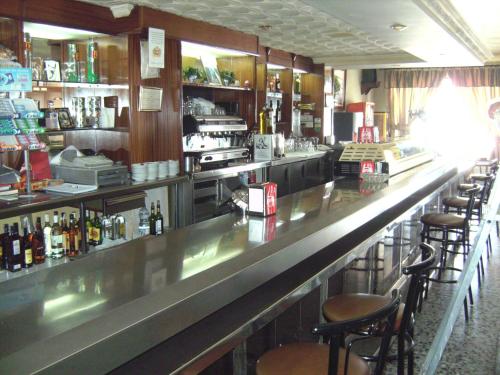 a bar with bar stools and bottles of alcohol at Hostal El Polígono in Lucena