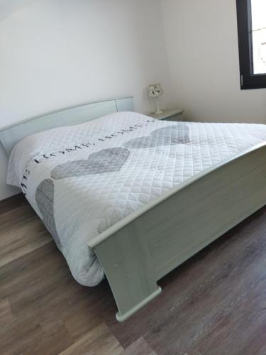 a bed with a white comforter in a bedroom at Chez Monique in Maubert-Fontaine