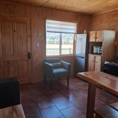 a kitchen with a table and a chair and a refrigerator at Cabaña Elizabeth in Cochrane