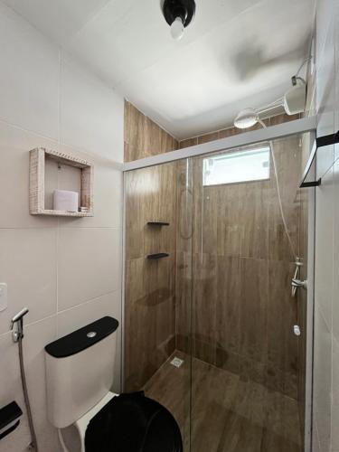 a bathroom with a toilet and a glass shower at Casinhas da toca in Búzios