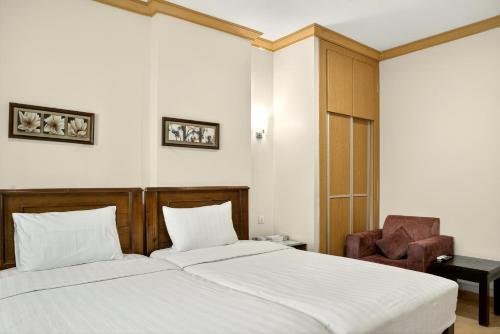 een slaapkamer met 2 bedden en een stoel bij Al Thill Hotel in Mekka