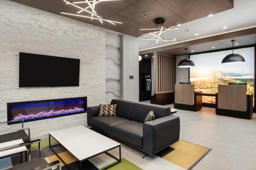 a living room with a couch and a tv on a brick wall at La Quinta Inn & Suites by Wyndham Kelowna BC in Kelowna